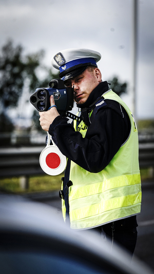 Policjant dokonuje pomiaru prędkości na drodze