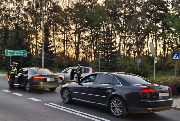 na zdjęciu nr 1 do 3 widoczny jest radiowóz oznakowany i dwóch umundurowanych policjantów dokonujących kontroli pojazdów osobowych