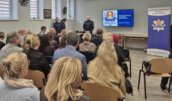 Człuchów, Bezpieczeństwo w szkołach pod lupą. Liczy się szybka reakcja i współpraca. Na załączonych zdjęciach widoczna jest sala, a w niej grupa dorosłych ludzi, która siedzi w jednym kierunku, w kierunku osób prowadzących spotkanie, tj.  3 umundurowanych Policjantów.